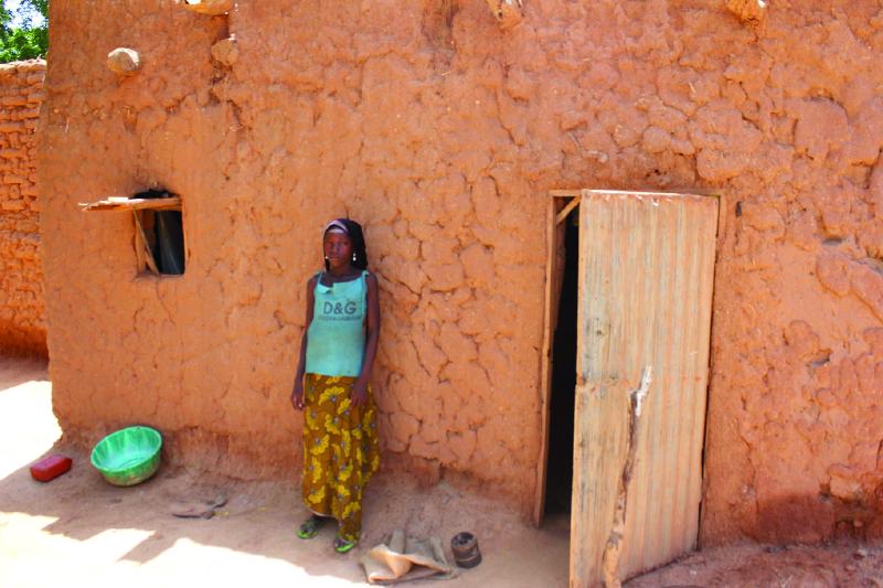 A Christian girl in front of her traditional home in a remote village in Niger